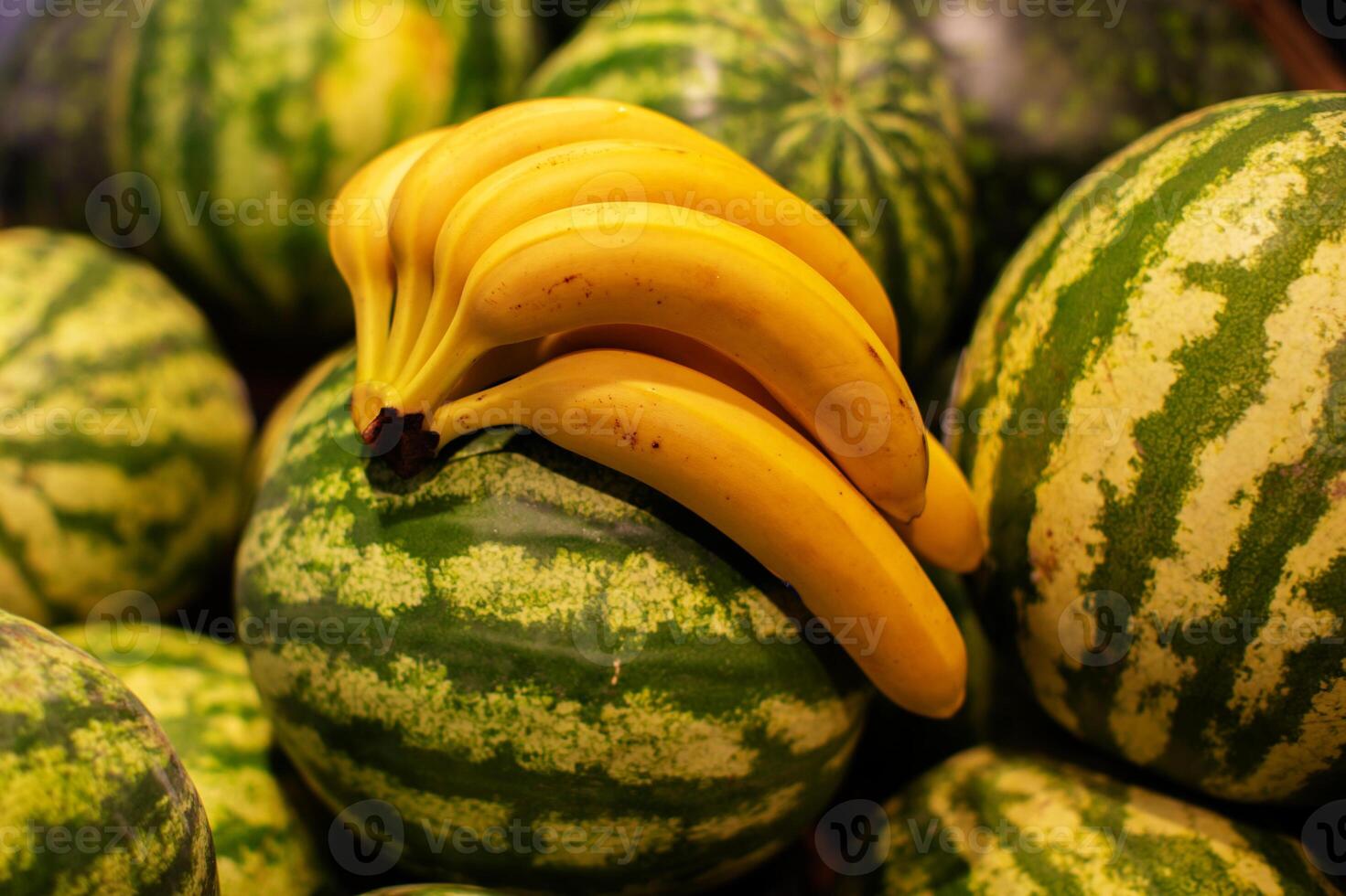 A branch of ripe bananas and a bunch of watermelons are on sale photo