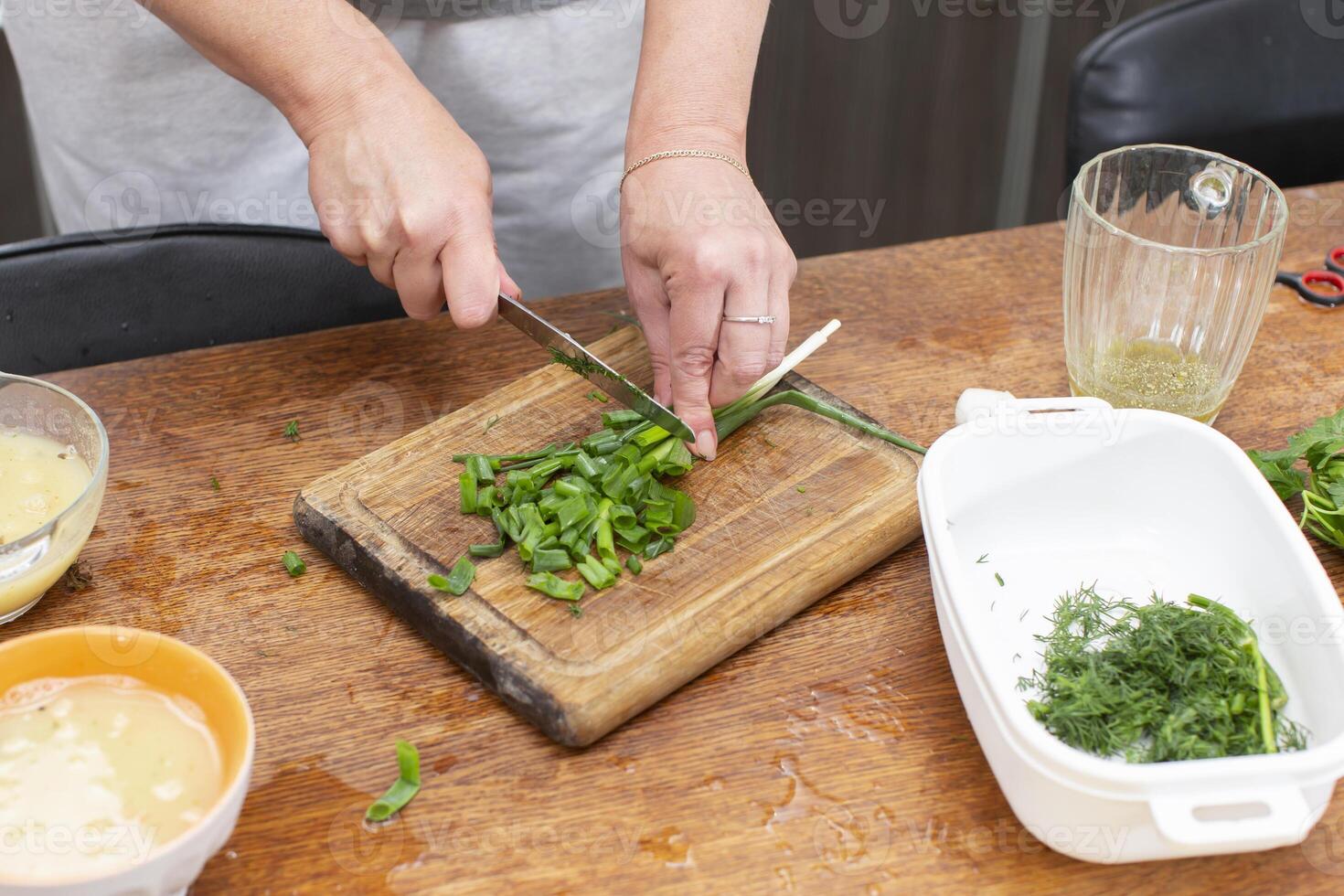Hands chop green onions on a cutting board. photo