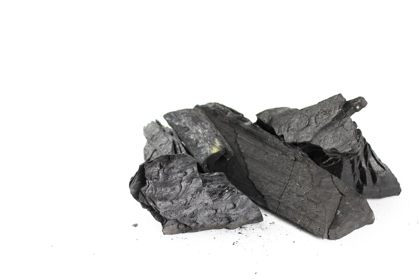 Isolated pieces of black charcoal resting on a clean white background photo