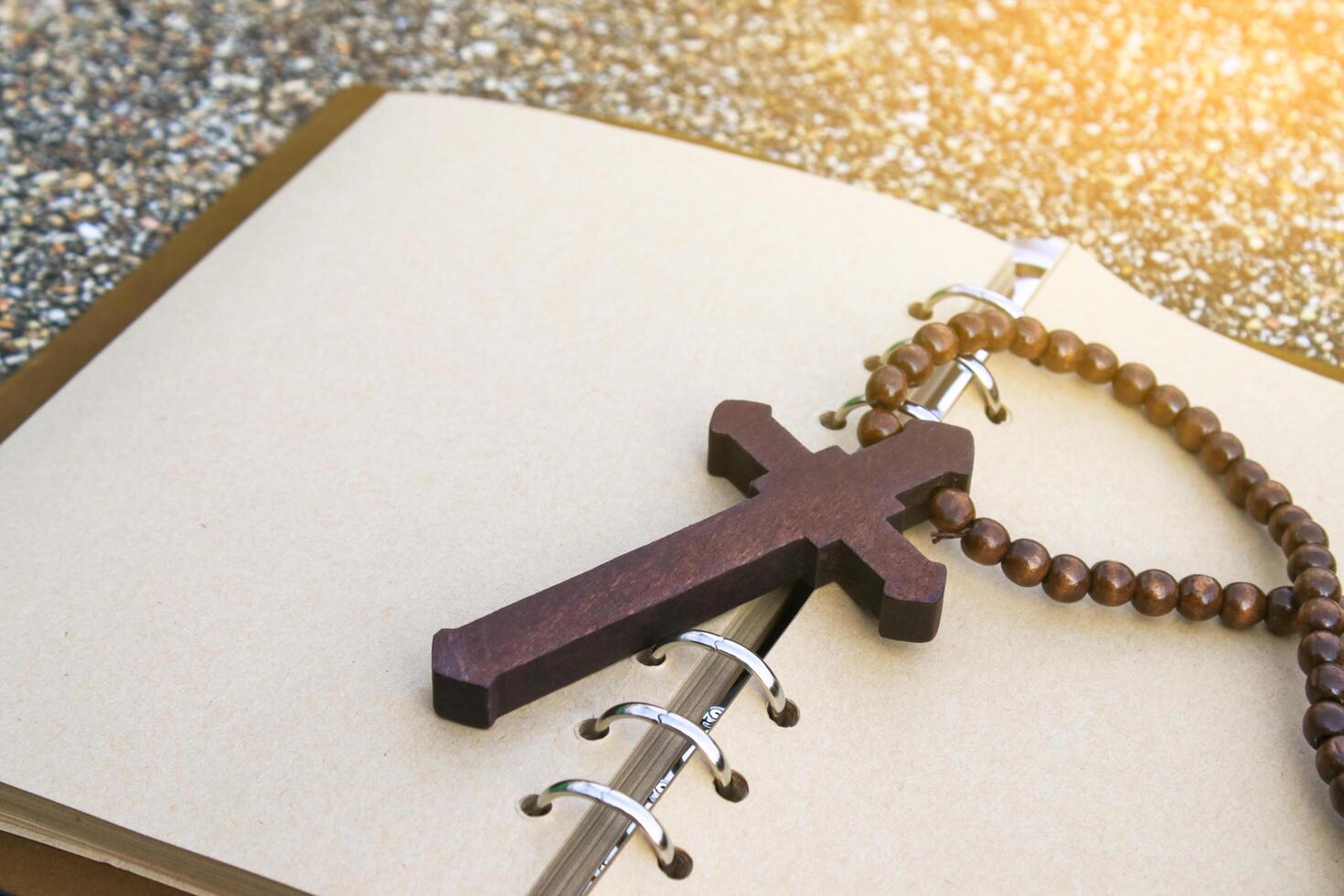 Simple wooden cross lies on an open brown notebook signifying humility, faith, and a connection to spirituality. This evokes thoughts of prayer, scripture study, and religious dedication. photo