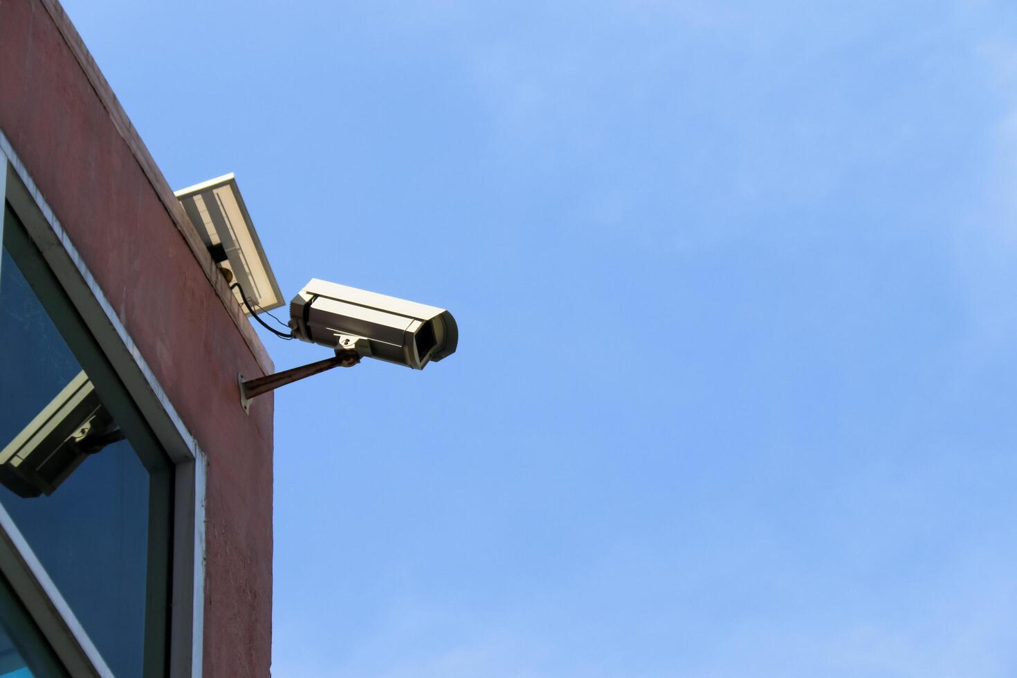 An old reliable CCTV camera mounted outdoors, exposed to sun and rain over the years, standing guard to ensure security for homes. A symbol of safety and modern surveillance technology. photo