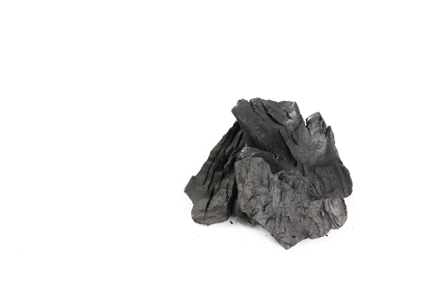 Isolated pieces of black charcoal resting on clean white background, showcasing its rough texture and deep, rich color. Often used for grilling, art, and filtration. photo