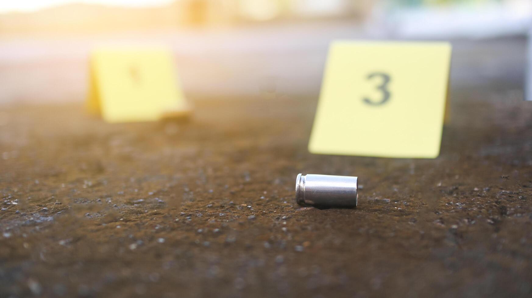 A spent bullet casing in focus, with a blurred forensic number 3 tag behind it, symbolizes crime scene investigation, evidence collection, and law enforcement efforts in forensic science. photo