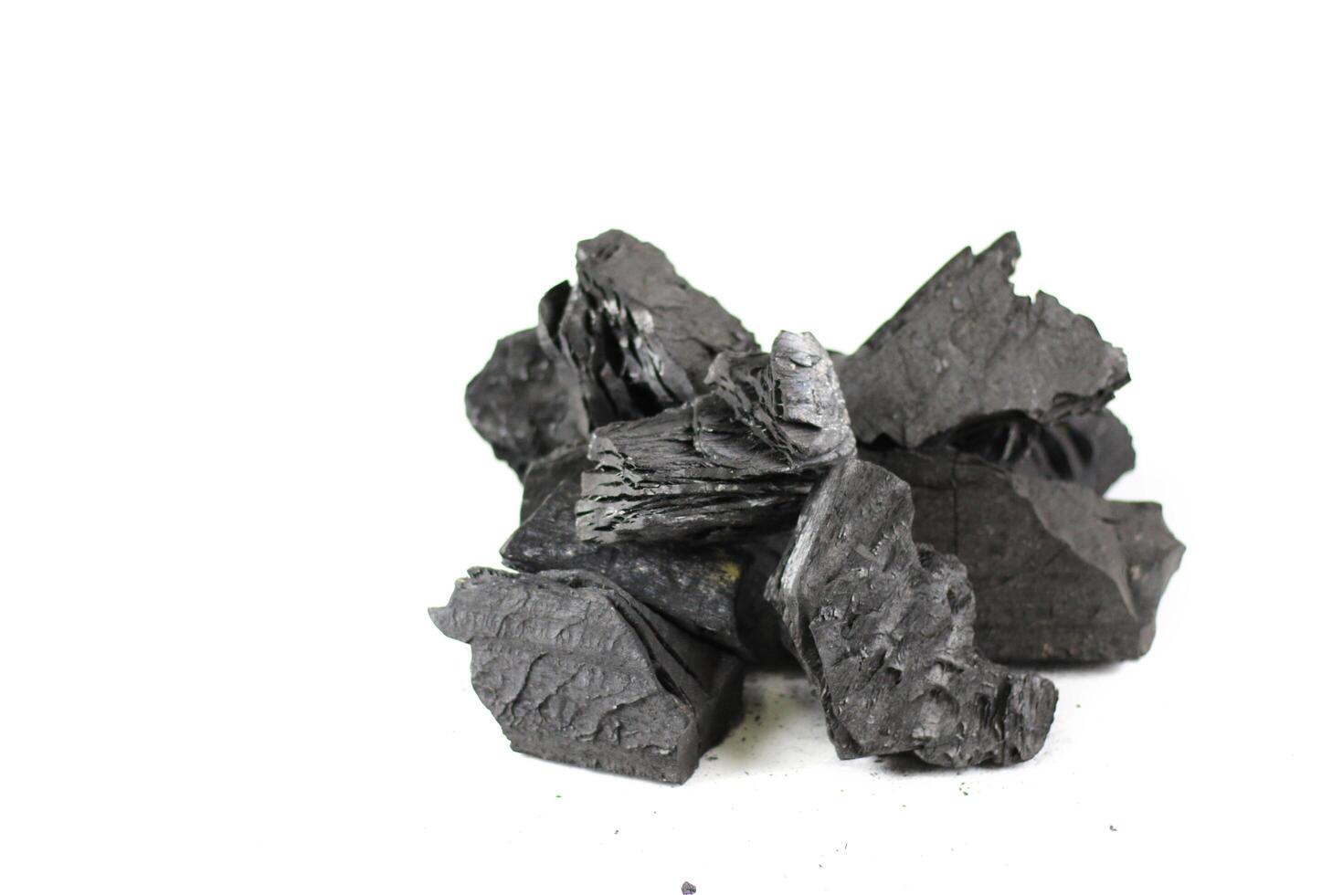 Isolated pieces of black wooden charcoal resting on white background, showcasing its rough texture and deep, rich color. Often used for grilling, art, and filtration. photo
