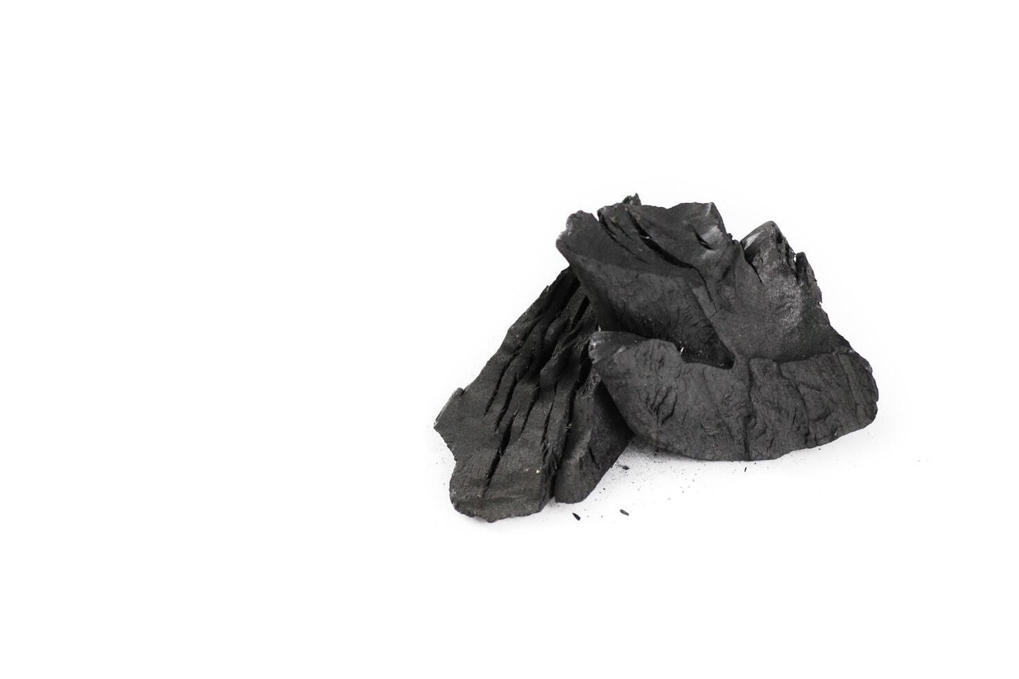 Isolated pieces of black charcoal resting on a clean white background. photo