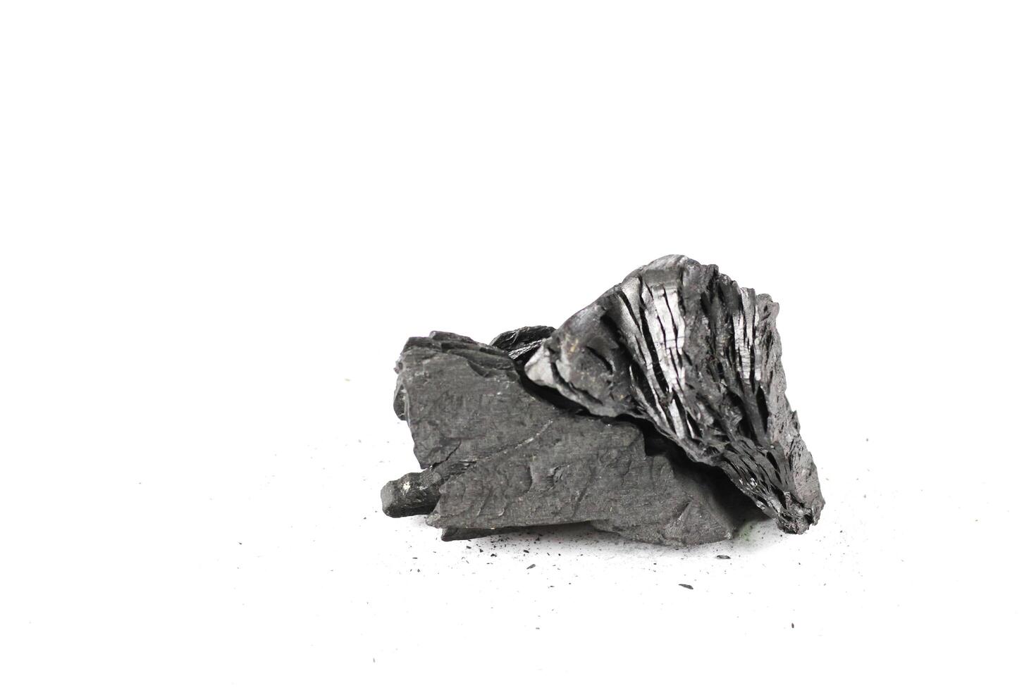 Isolated pieces of black charcoal resting on a clean white background, showcasing its rough texture and deep, rich color. Often used for grilling. photo