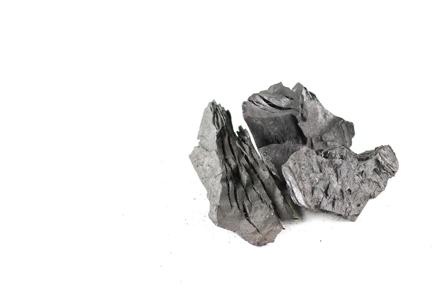 Isolated pieces of black charcoal on a white background, showcasing its rough texture and deep, rich color. Often used for grilling, art, and filtration. photo