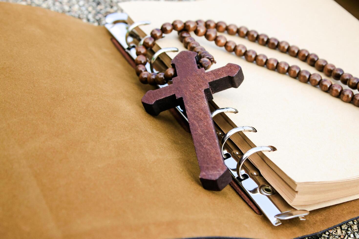 Simple wooden cross lies on an open brown notebook, signifying humility, faith, and a connection to spirituality. This evokes thoughts of prayer, scripture study, and religious dedication. photo