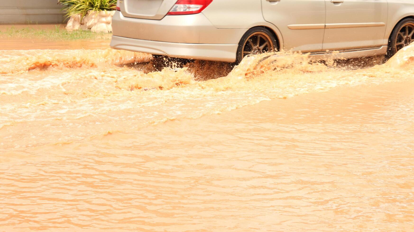 Vehicle navigates through muddy floodwater depicting urban resilience and the impact of heavy rain. This image highlights extreme weather, climate change, and transportation challenges. photo