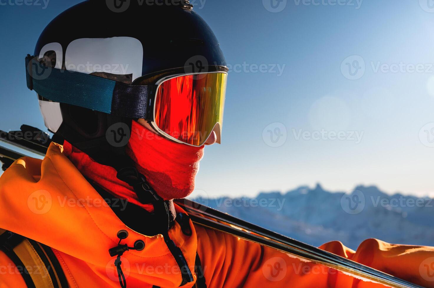 skiing downhill, skier on winter vacation against the backdrop of rocky snow-capped mountains stands with skis in his hands, putting them on his shoulders photo