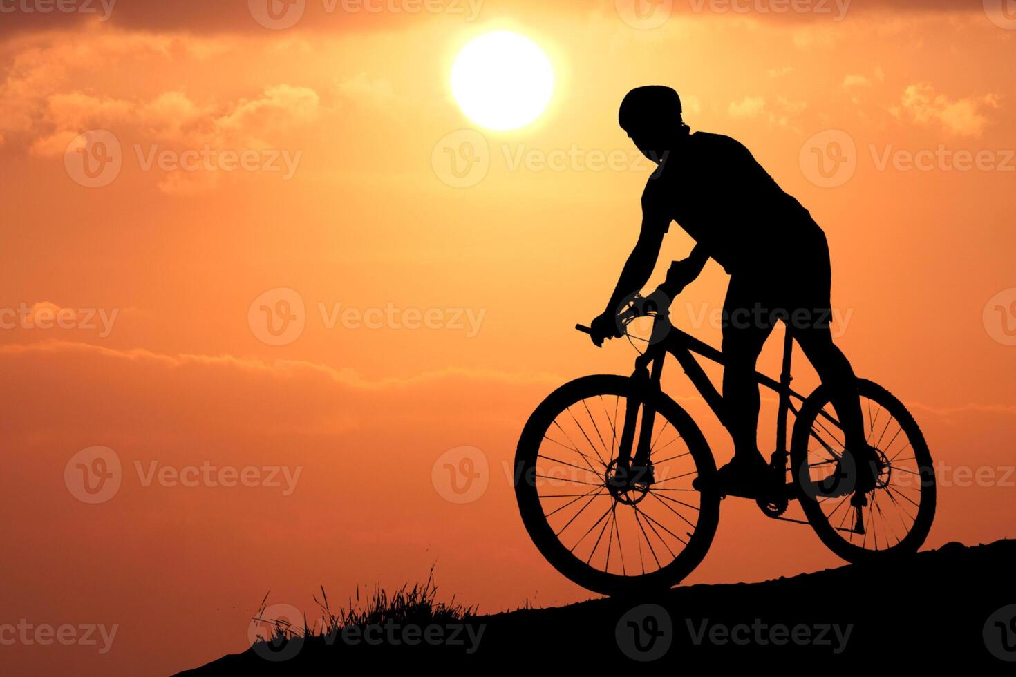 Silhouette of a Cyclist Riding a Mountain Bike Against a Vibrant Sunset Sky on a Scenic Hilltop photo