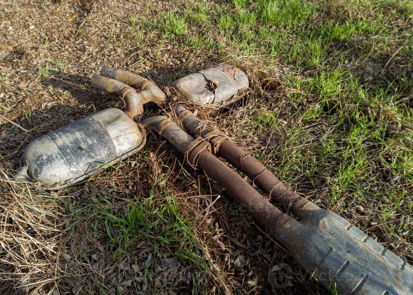 Discarded Rusty Exhaust System on Grass photo