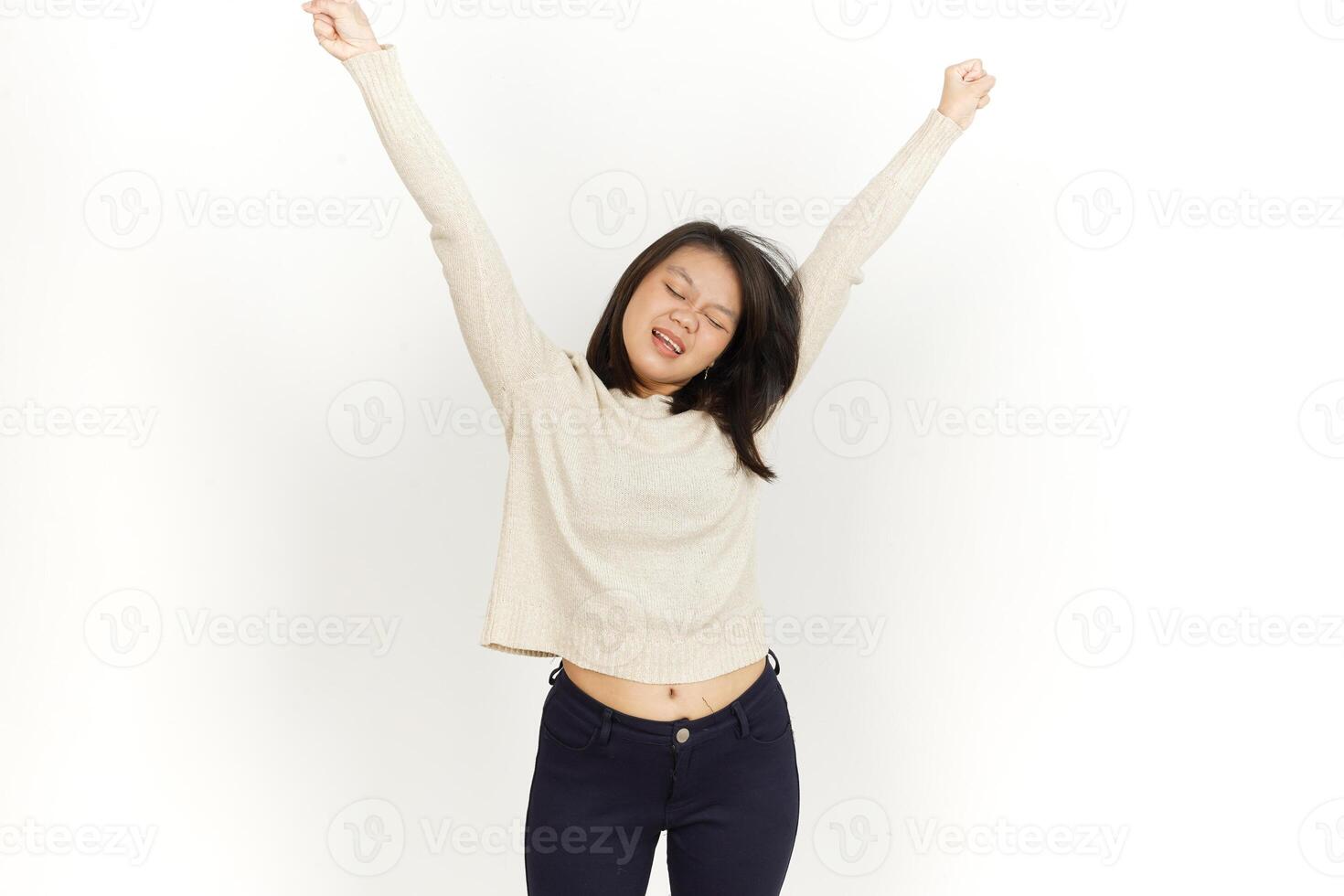 A woman in a sweater and jeans is standing with her arms up photo