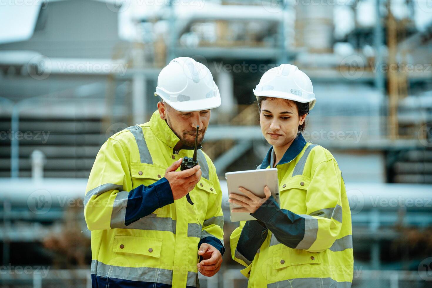 Workers collaborating at industrial site with communication device and tablet during project review photo