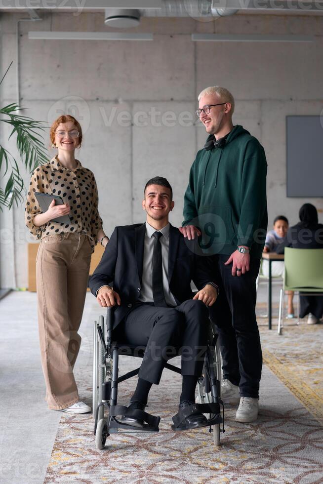 Group cheerful business colleagues, including a businessman in a wheelchair, posing together in a modern office, showcasing teamwork and inclusivity photo