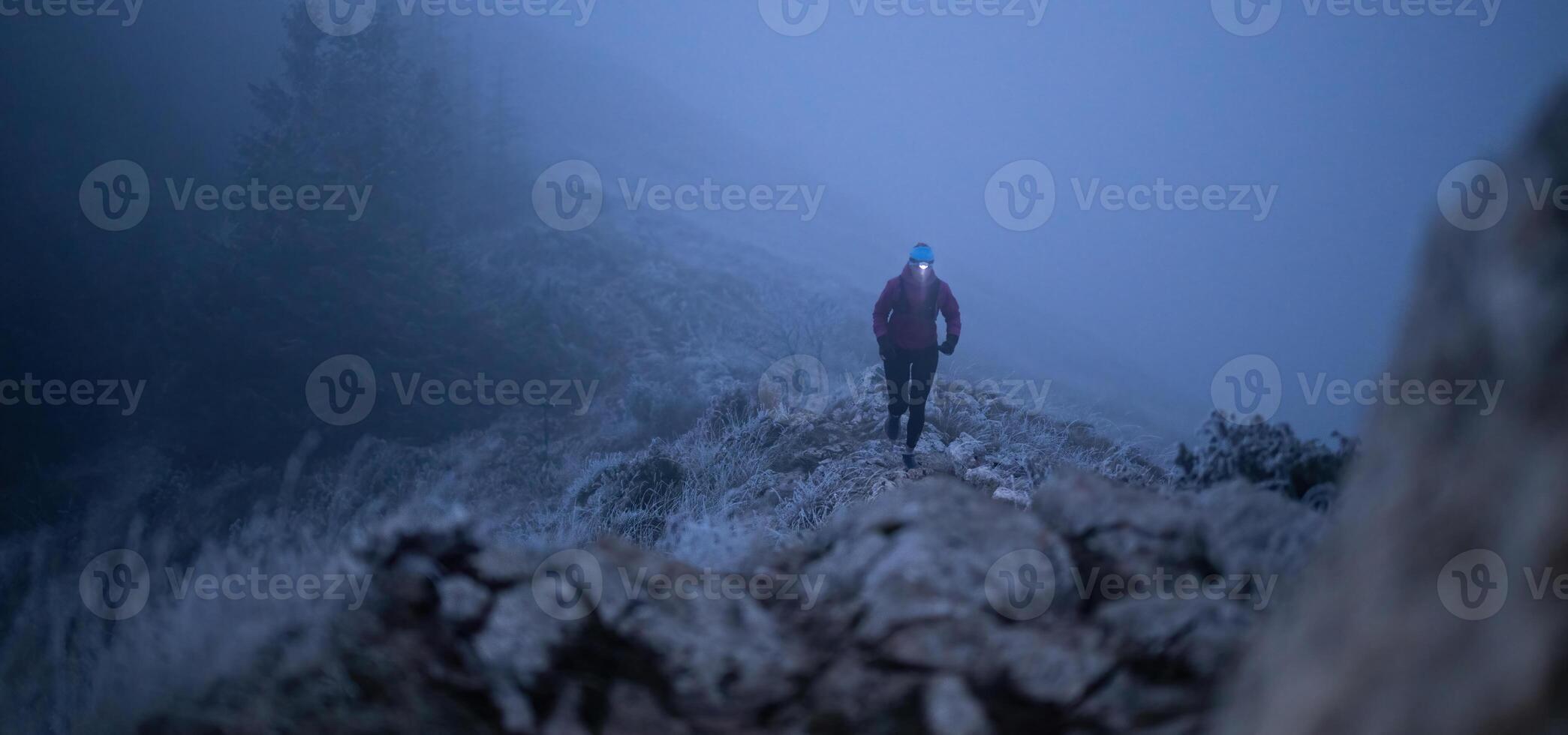 Determined Woman Trail Running at Night, Illuminated by a Headlamp in the Mountain Wilderness. photo
