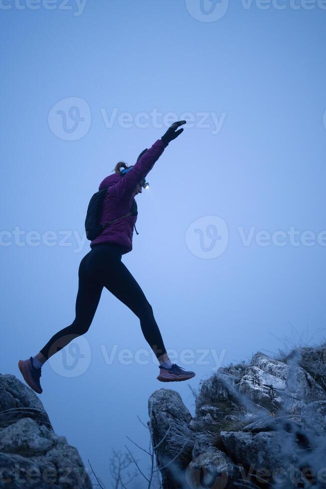 Determined Woman Trail Running at Night, Illuminated by a Headlamp in the Mountain Wilderness. photo