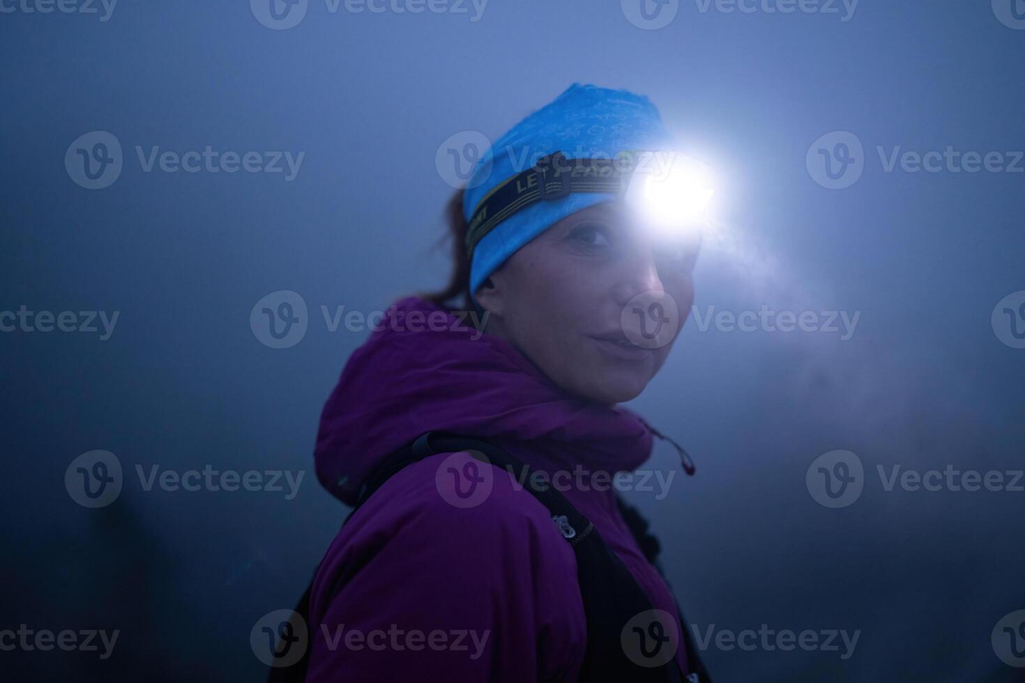 Determined Woman Trail Running at Night, Illuminated by a Headlamp in the Mountain Wilderness. photo