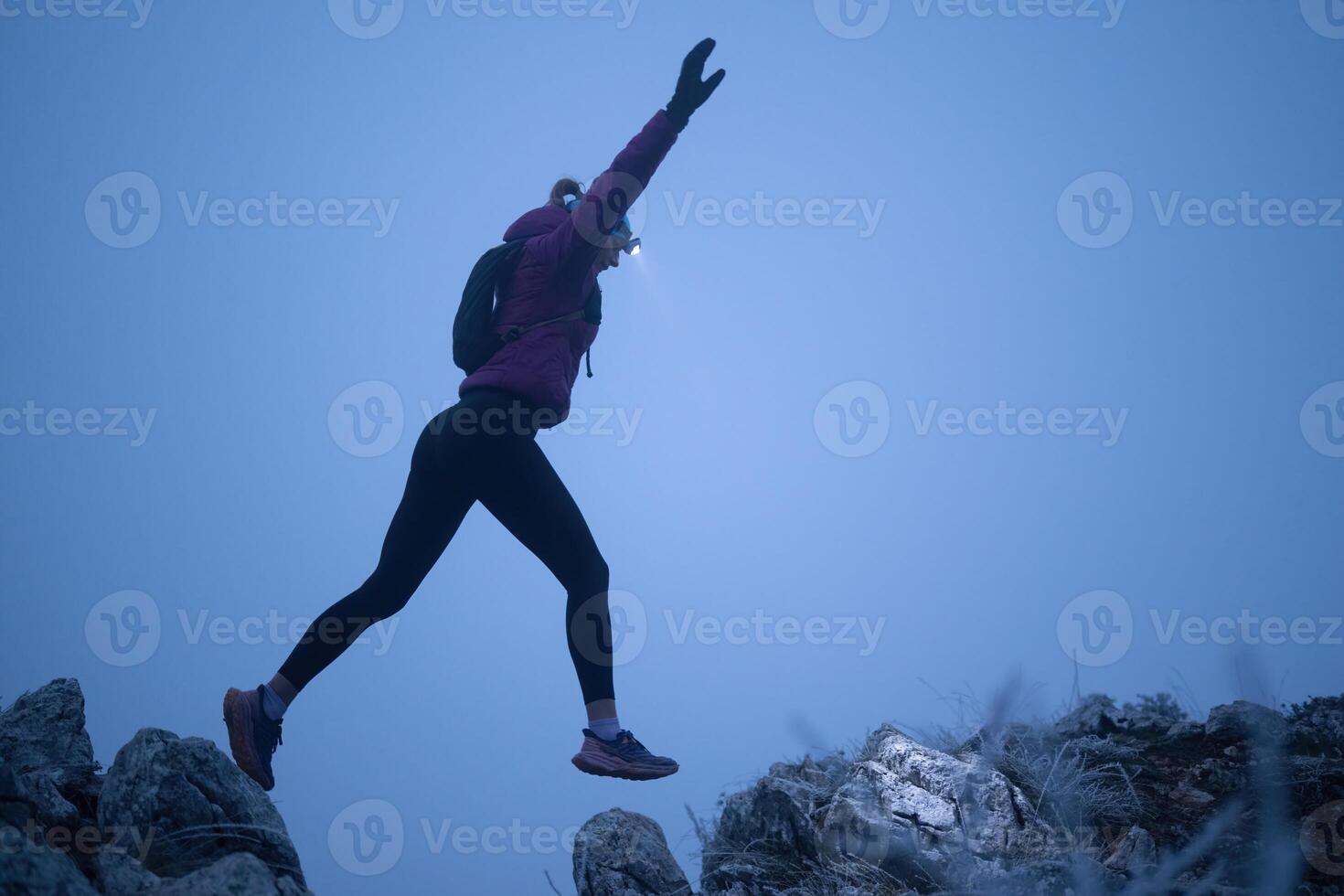 Determined Woman Trail Running at Night, Illuminated by a Headlamp in the Mountain Wilderness. photo