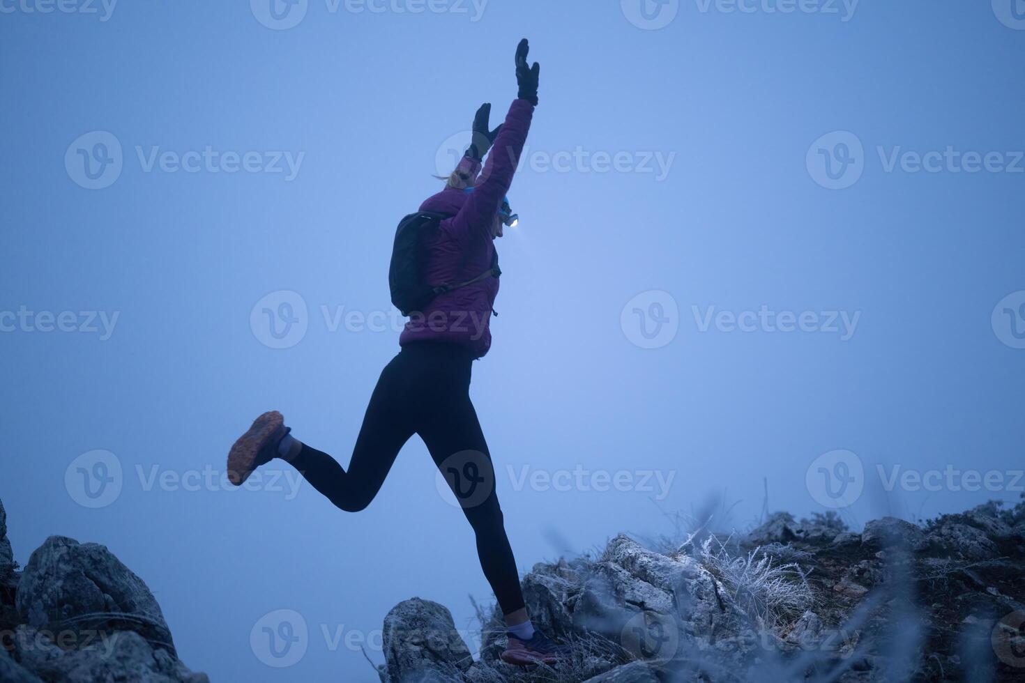 Determined Woman Trail Running at Night, Illuminated by a Headlamp in the Mountain Wilderness. photo
