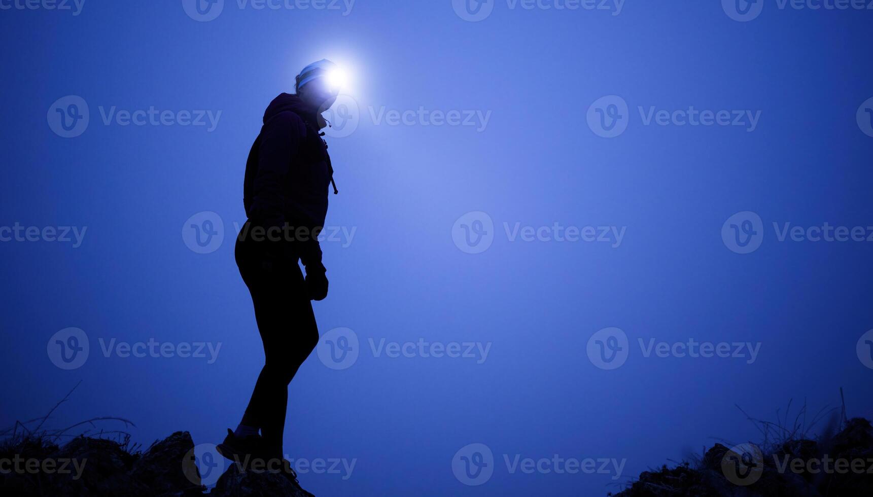 Determined Woman Trail Running at Night, Illuminated by a Headlamp in the Mountain Wilderness. photo