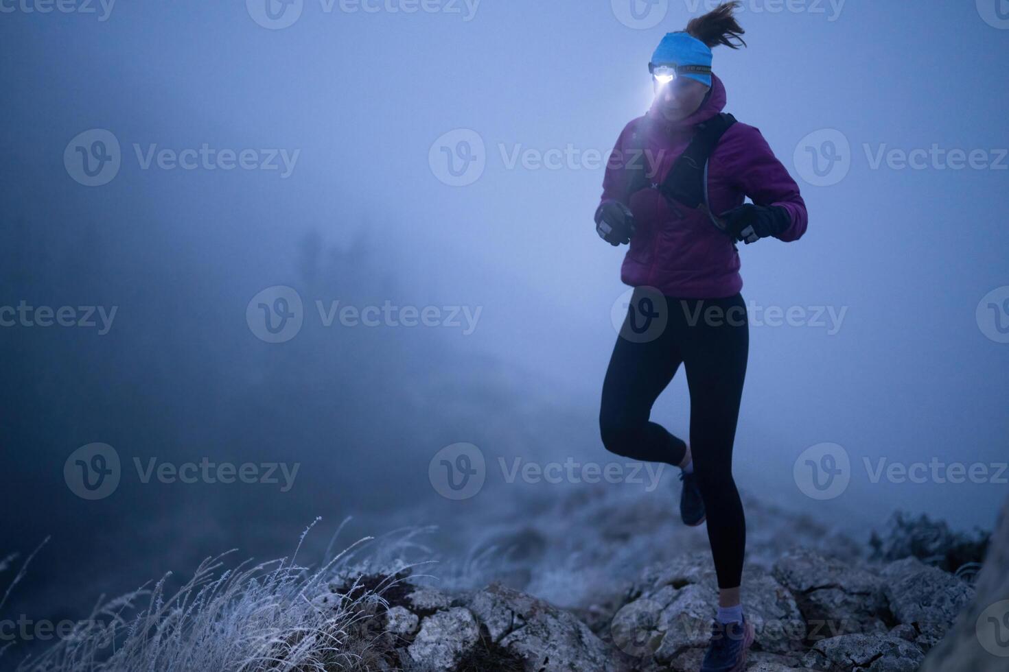 Determined Woman Trail Running at Night, Illuminated by a Headlamp in the Mountain Wilderness. photo