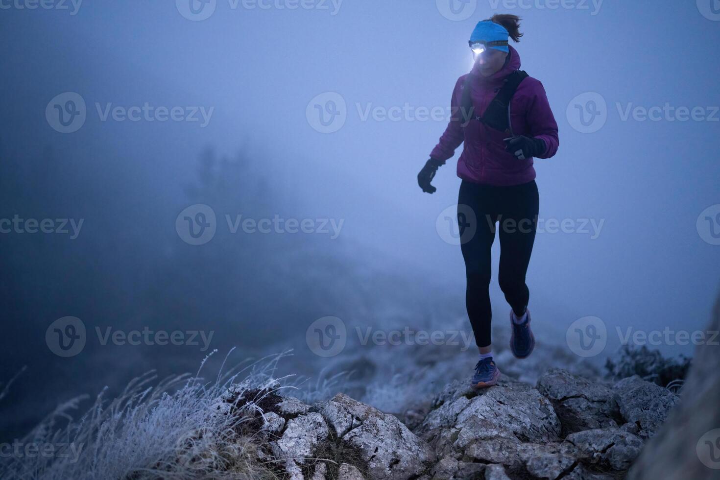 Determined Woman Trail Running at Night, Illuminated by a Headlamp in the Mountain Wilderness. photo
