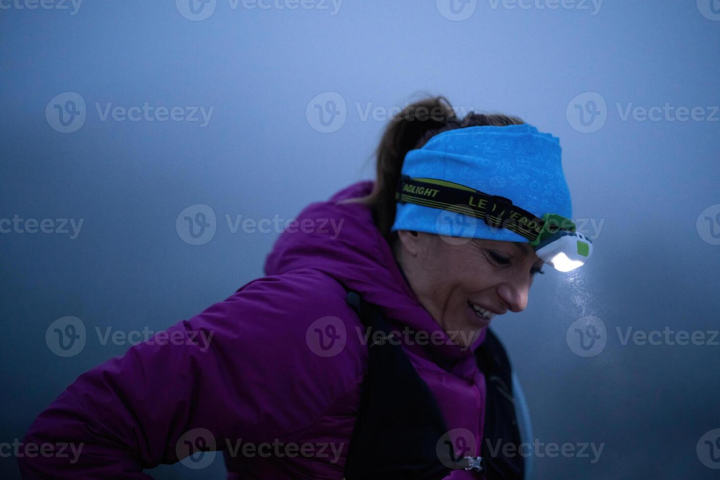 Determined Woman Trail Running at Night, Illuminated by a Headlamp in the Mountain Wilderness. photo