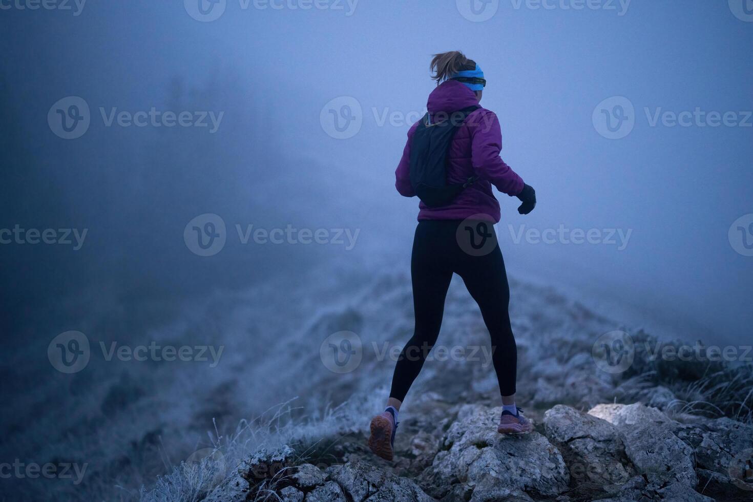 Determined Woman Trail Running at Night, Illuminated by a Headlamp in the Mountain Wilderness. photo
