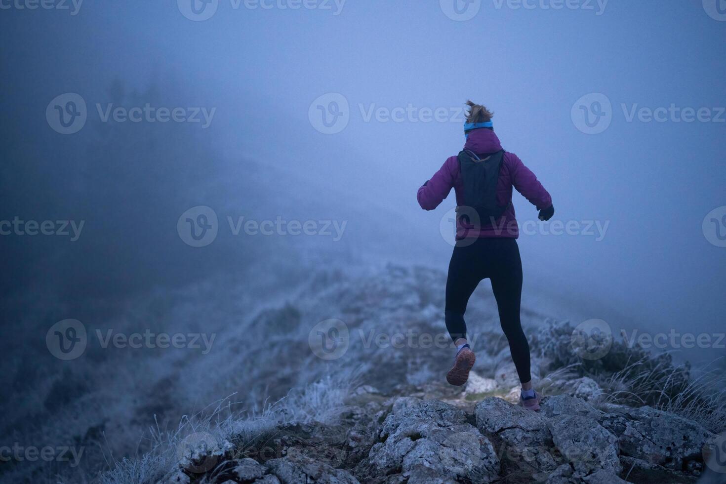 Determined Woman Trail Running at Night, Illuminated by a Headlamp in the Mountain Wilderness. photo