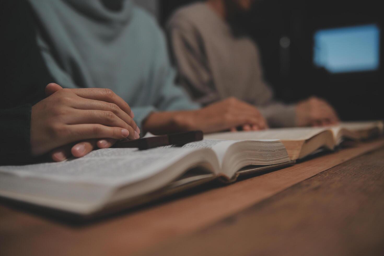 Two people are sitting at a table with an open book photo