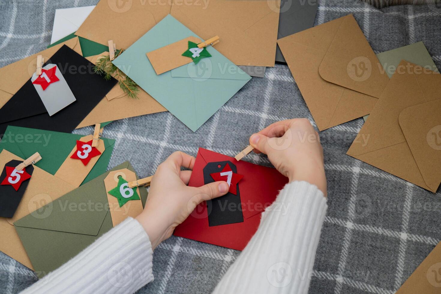 Number on craft envelopes notes with tasks before Christmas holidays. Female making kraft paper for handmade advent calendar Made with your own hands step by step DIY crafts do it yourself photo