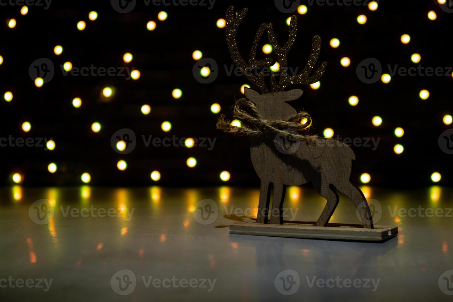 Reindeer wooden on dark bokeh light garland background. New year and Christmas preparation. Handmade eco-friendly decor. Sustainable Christmas decoration. Copy space photo