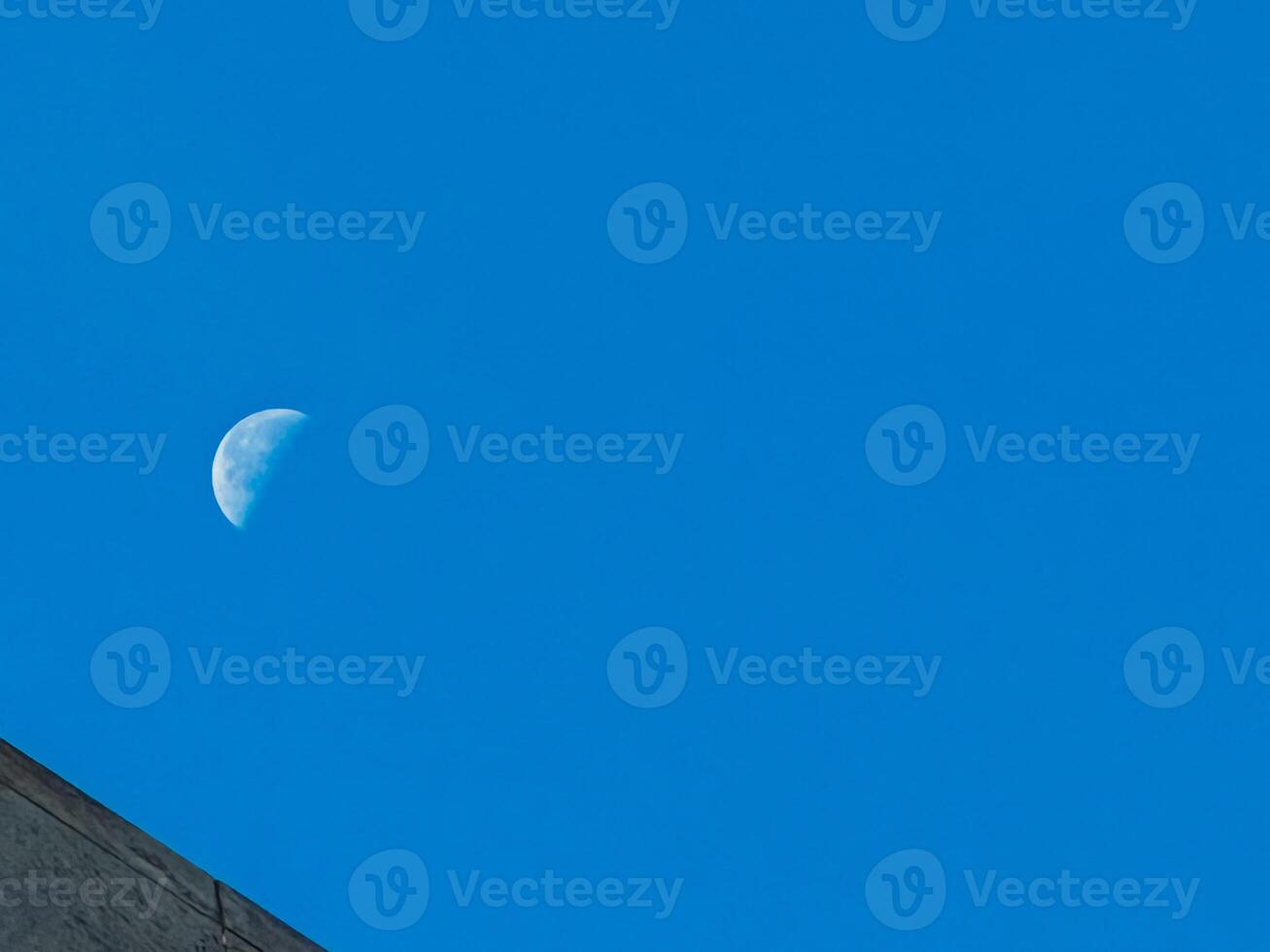 A large moon is visible in the sky above a blue sky photo