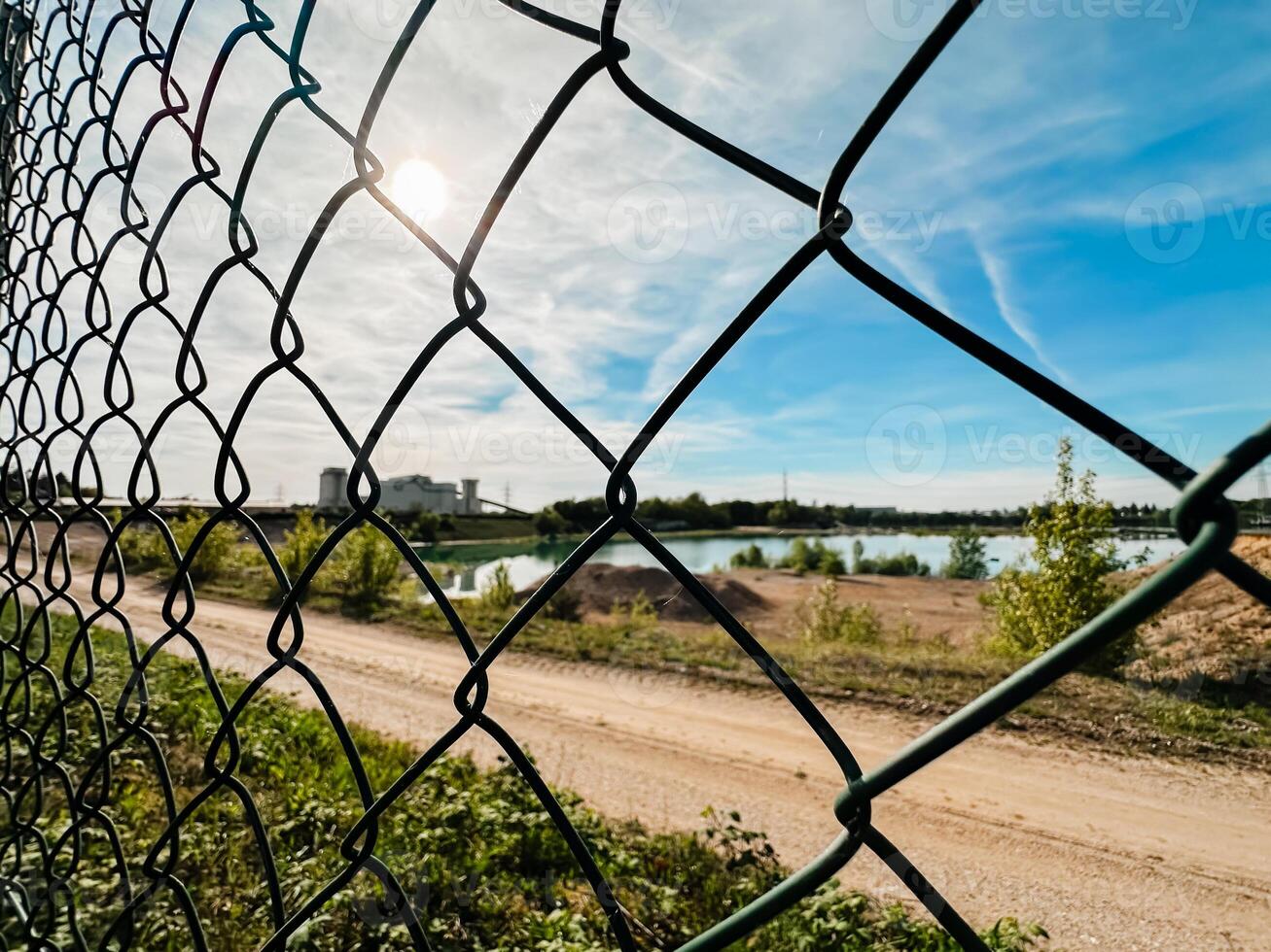 A chain link fence with a view of a lake and a building in the background photo