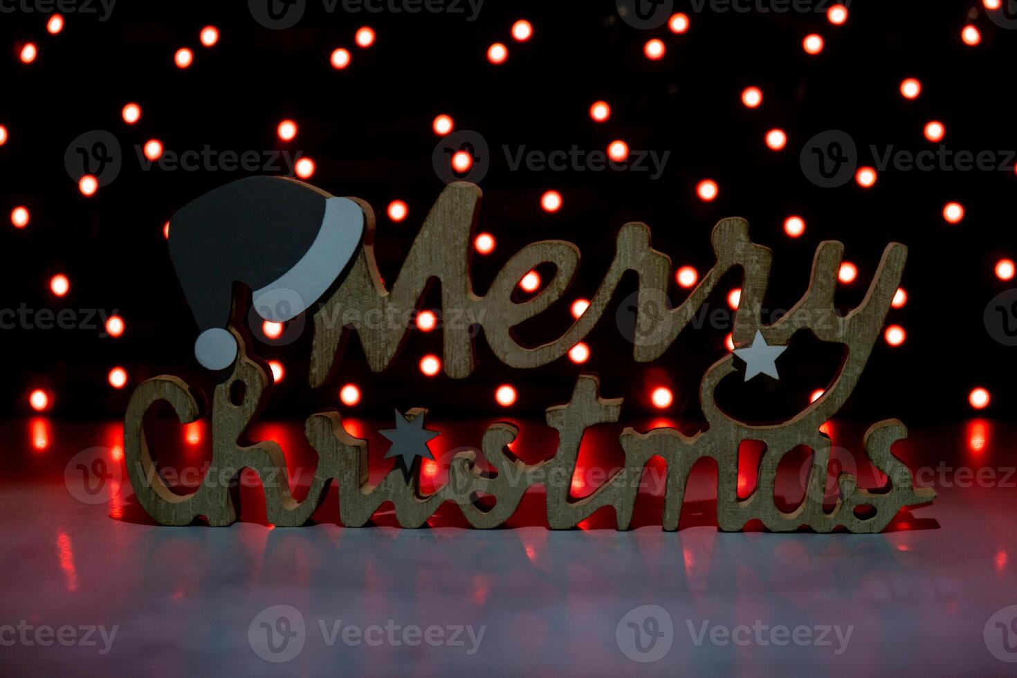 Merry Christmas wooden message on dark bokeh light garland background. New year and Christmas preparation. Handmade eco-friendly decor. Sustainable Christmas decoration photo