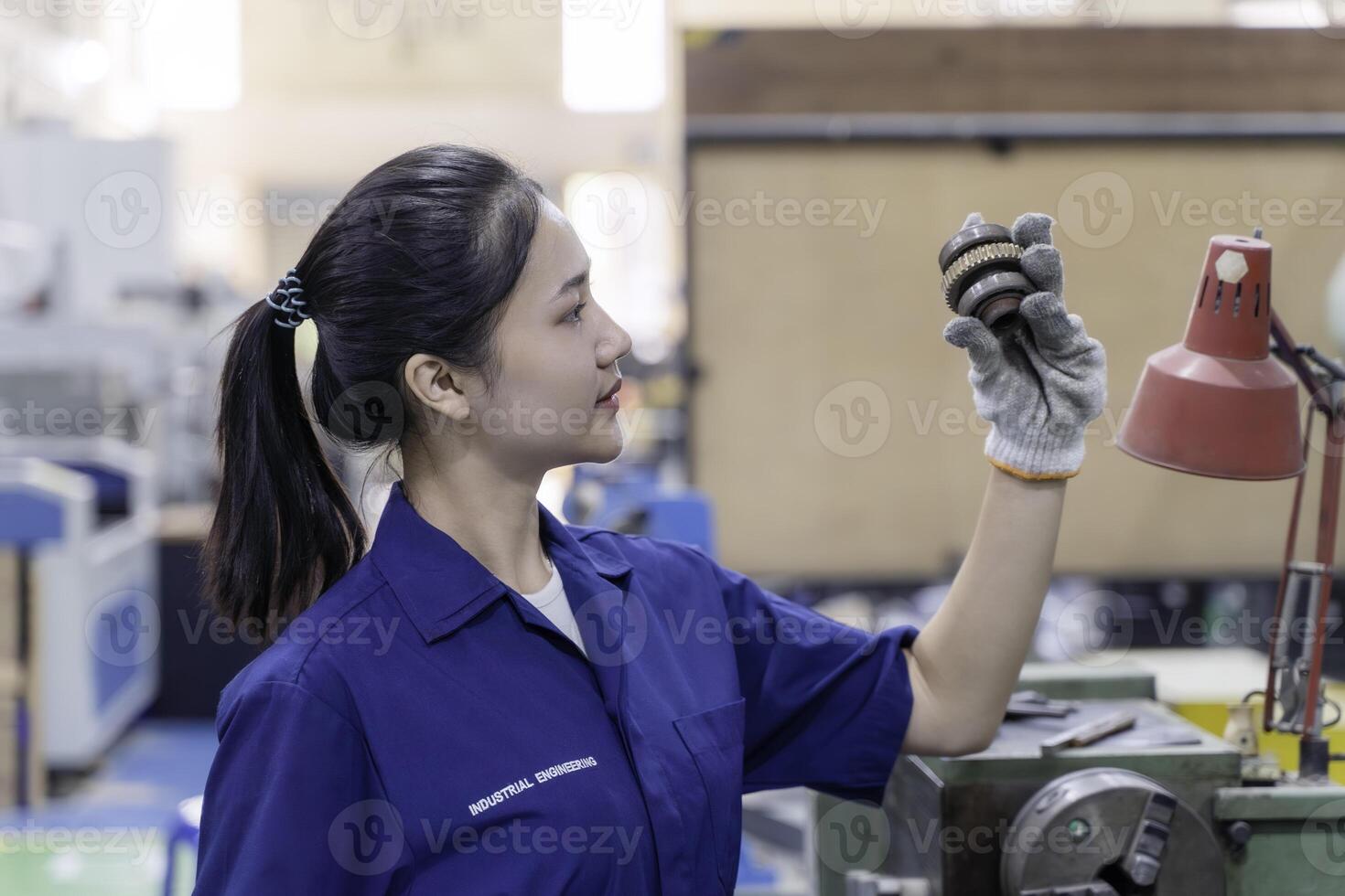 Closeup Asian woman technician engineer hold and looking check example small gear photo