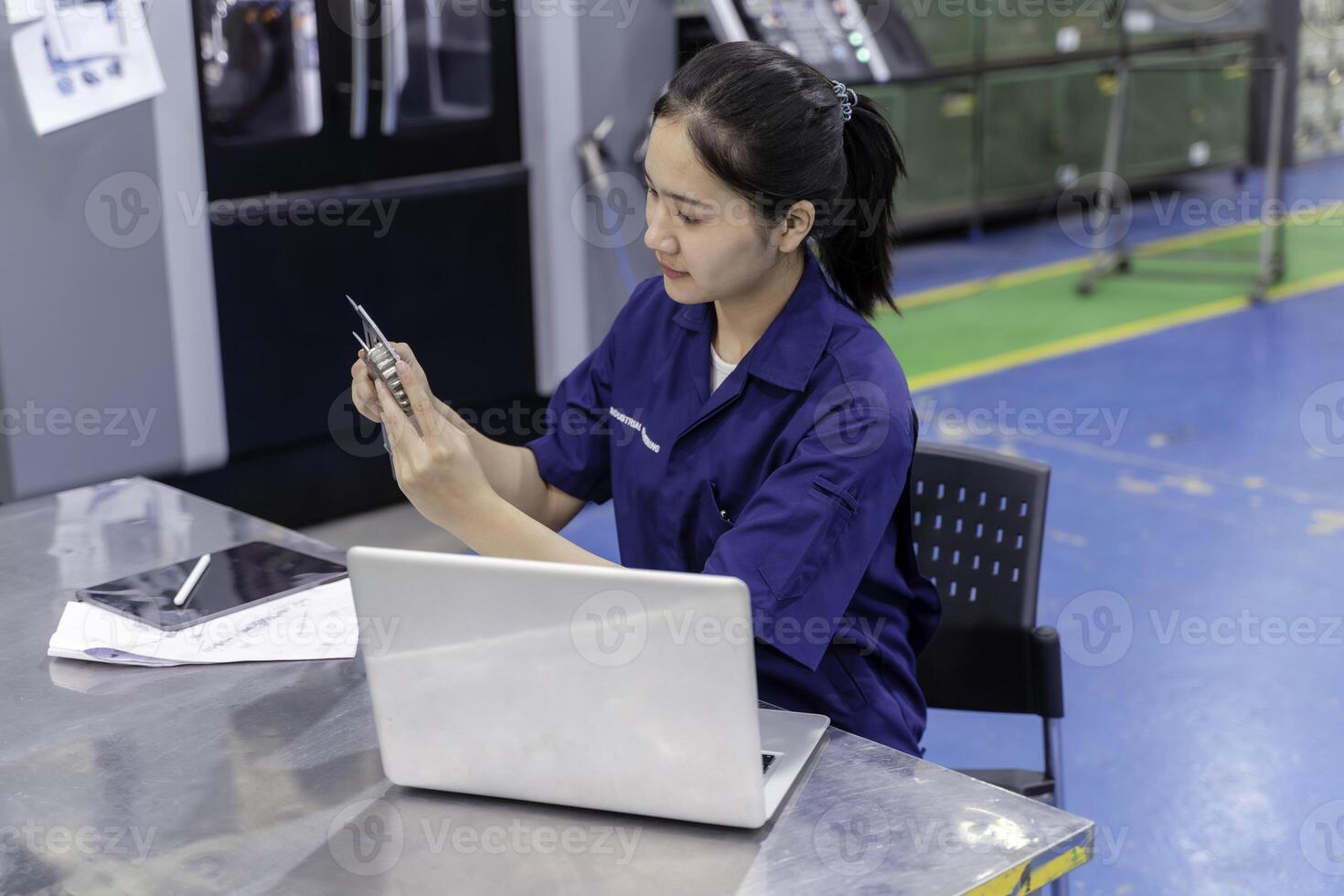 Asian woman technician engineer working designing mechanical parts engineering with laptop and checking an example small gear with metal ruler photo