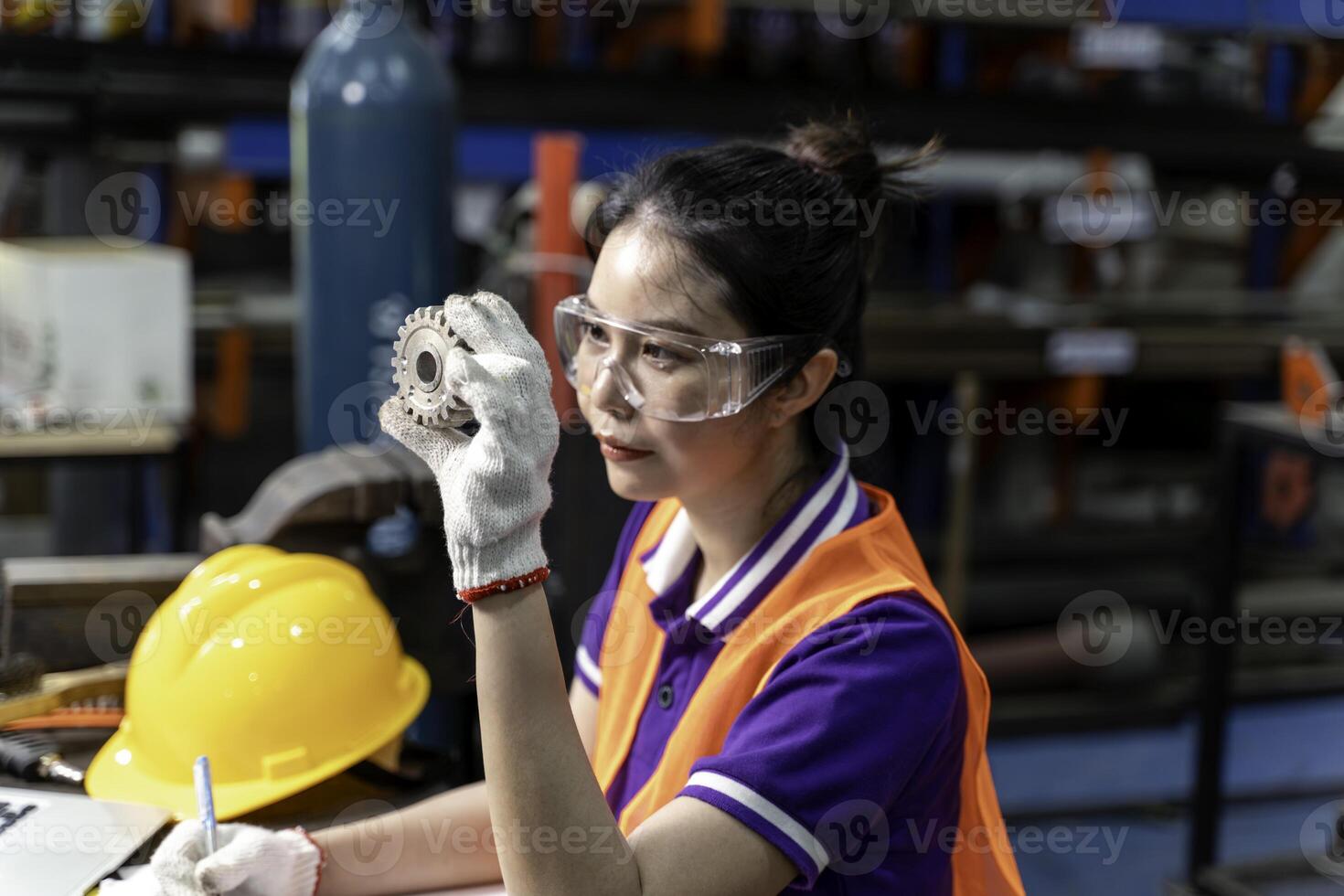 Closeup Asian woman industrial engineer hold and looking example small gear to working designing mechanical parts engineering photo