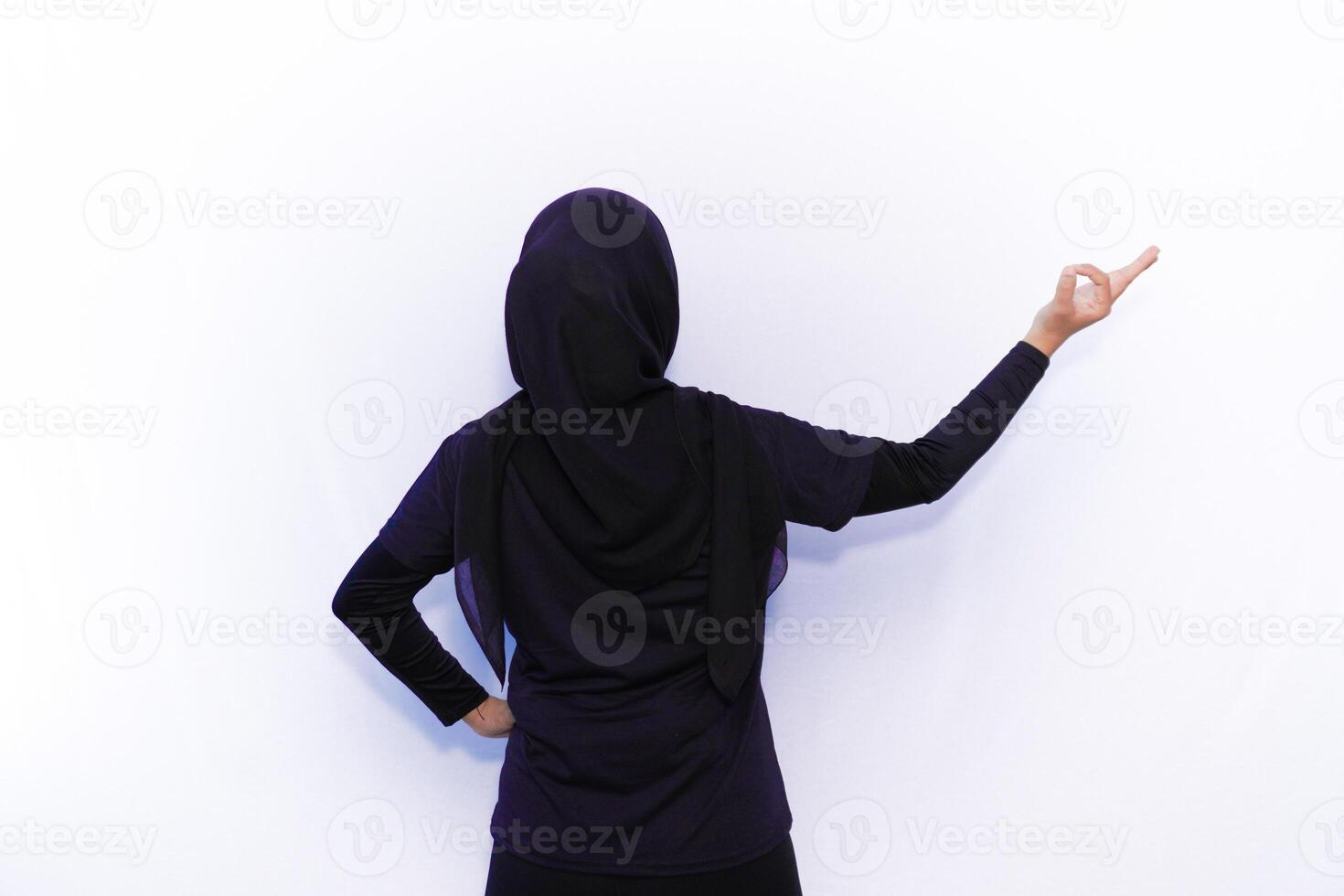 back view of muslim woman in black hijab pointing to something photo