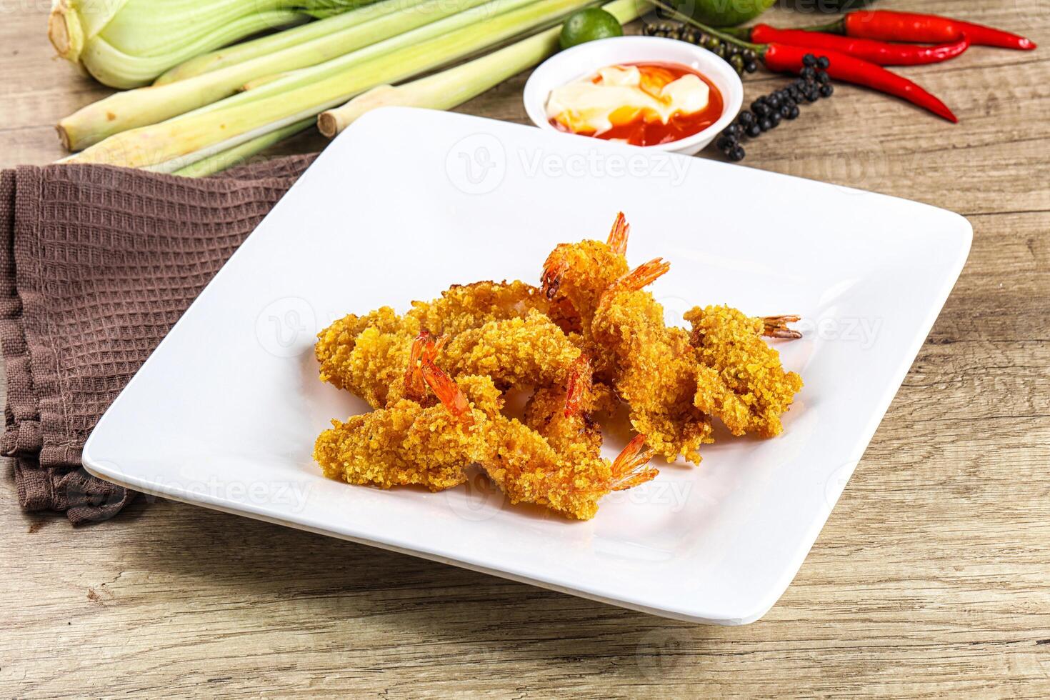 A plate of fried shrimp on a table with other food photo