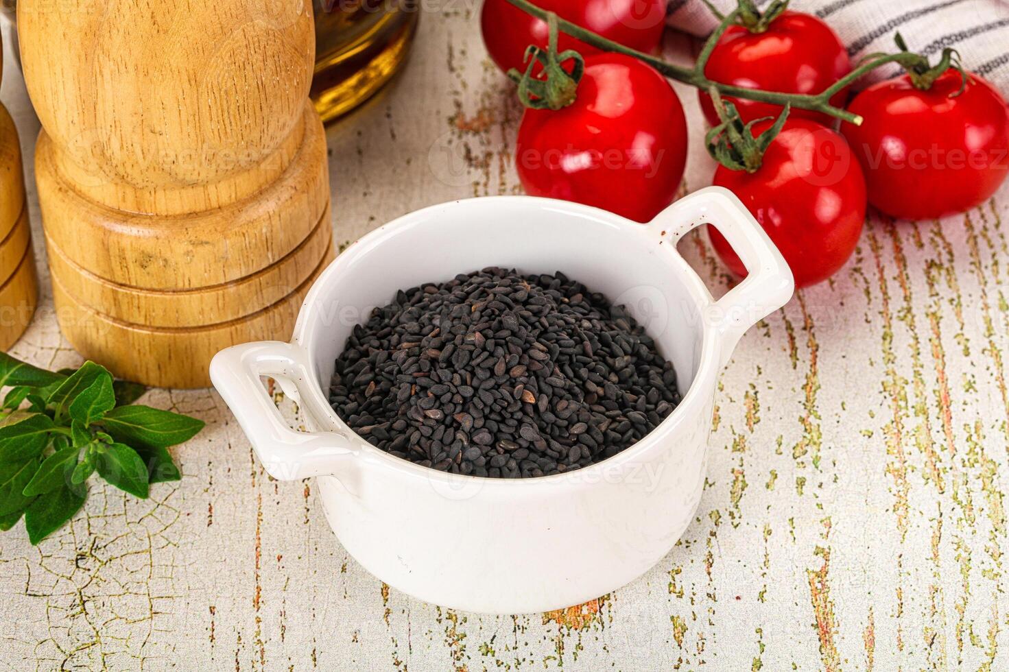 A bowl of black seeds next to a bottle of olive oil photo