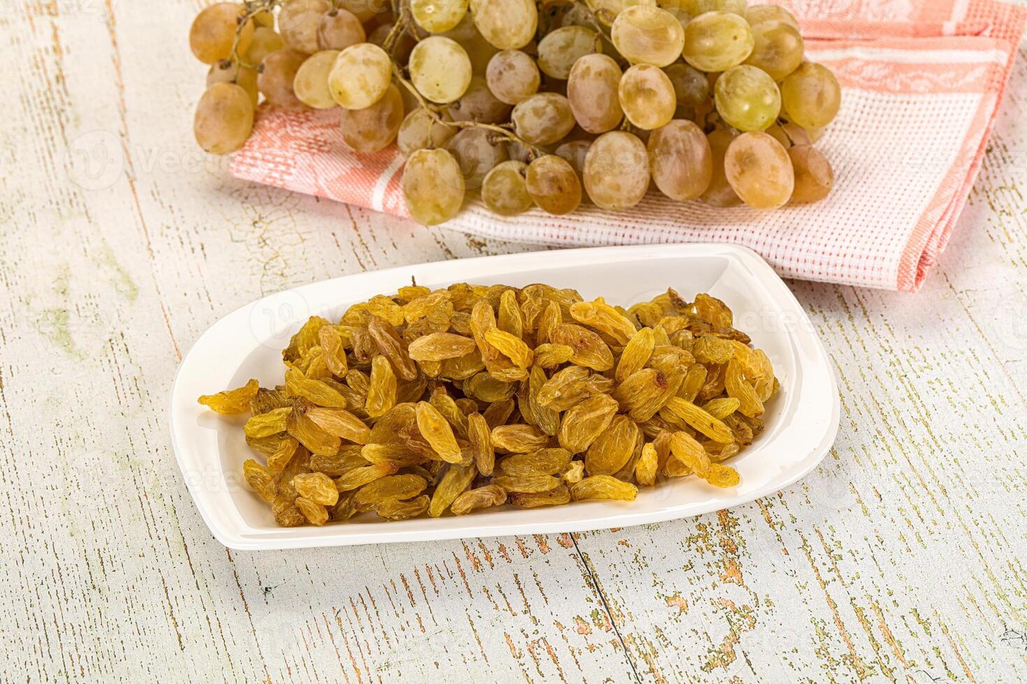 A bowl of raisins and a plate of grapes photo