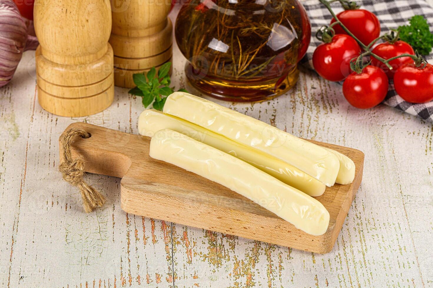 A wooden cutting board with cheese and tomatoes photo