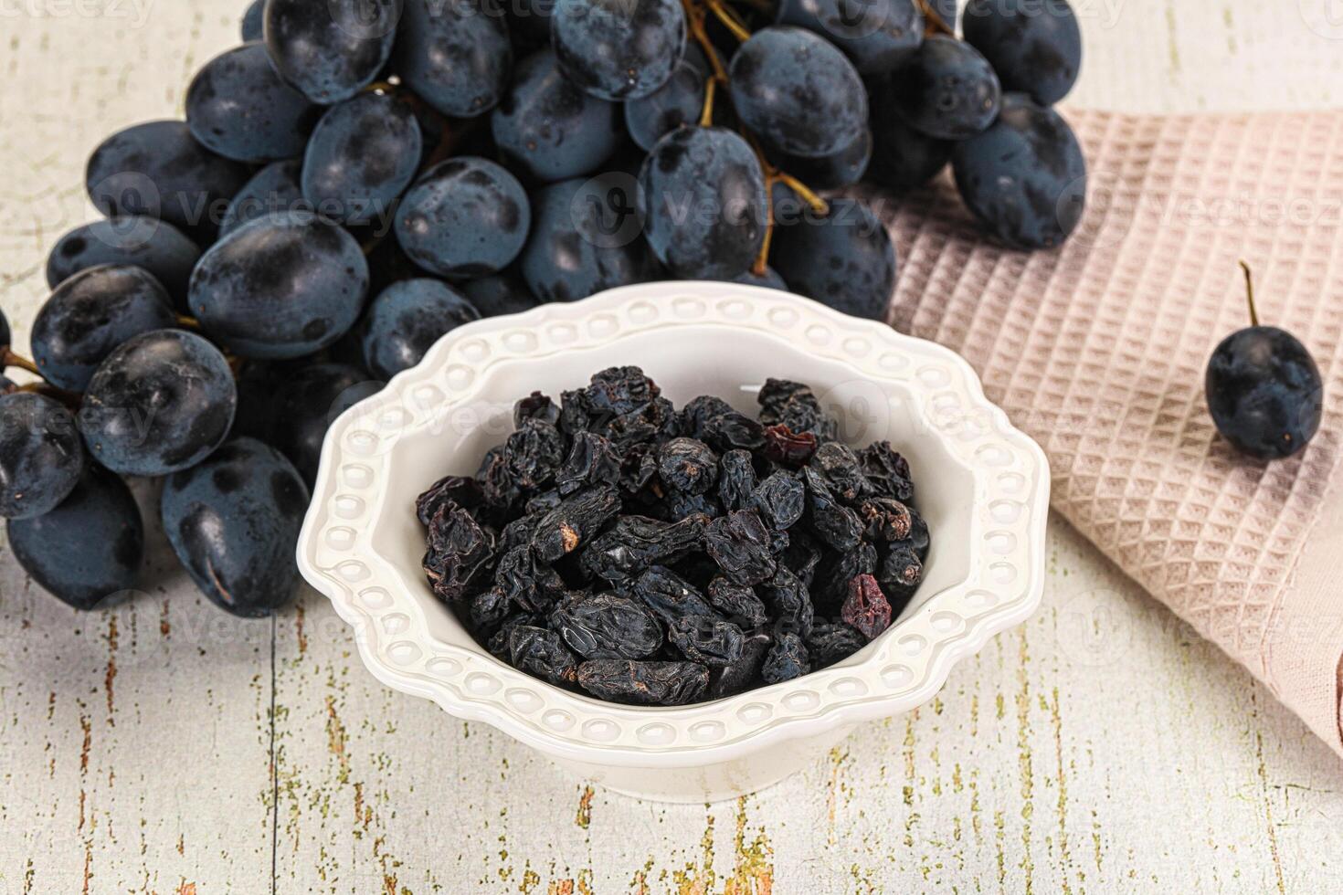 A bowl of dried black grapes on a table photo