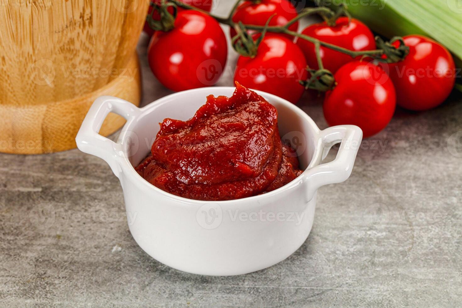 A bowl of tomato sauce next to a wooden chopping board photo