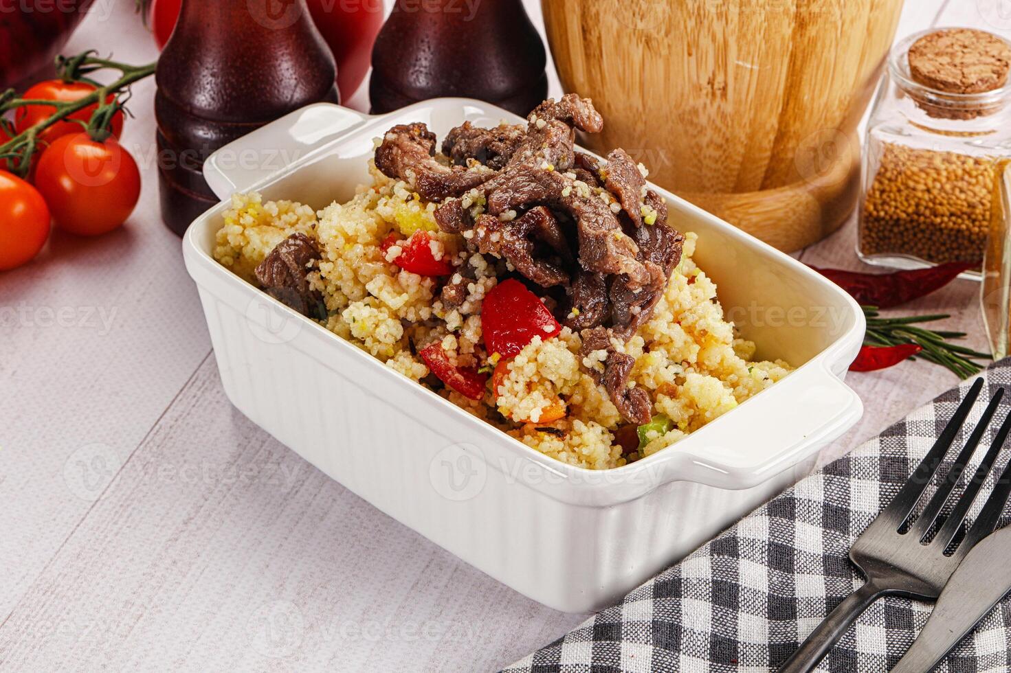 A white dish with meat and vegetables on a table photo