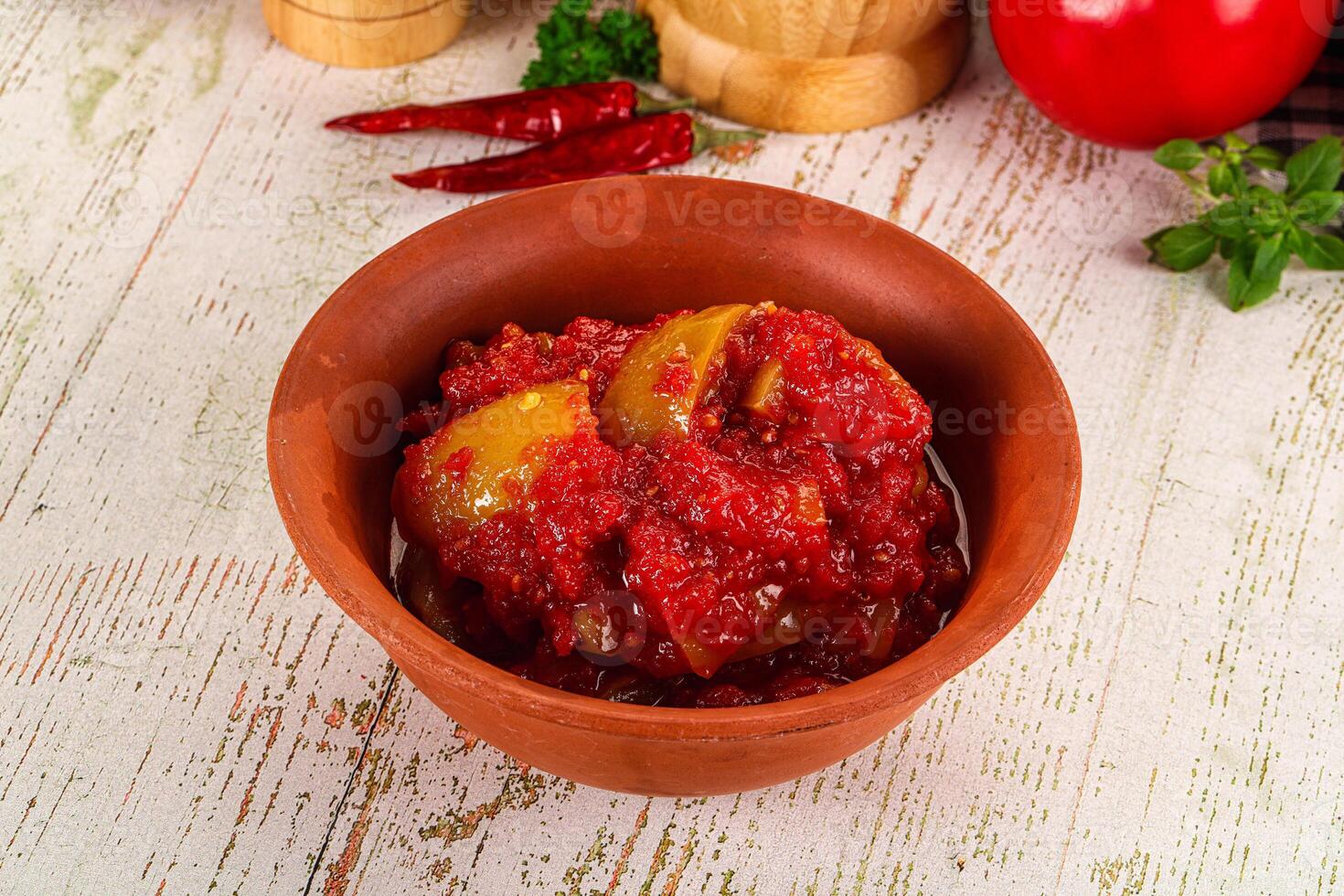A bowl of tomato sauce with some peppers and herbs photo
