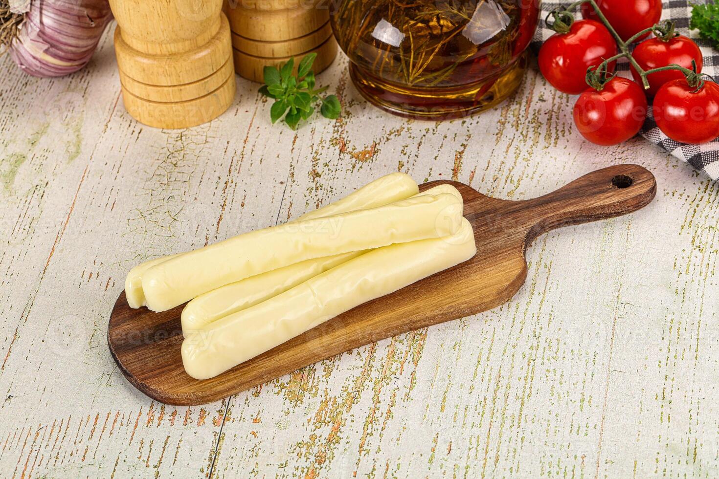 A wooden cutting board with cheese sticks on it photo
