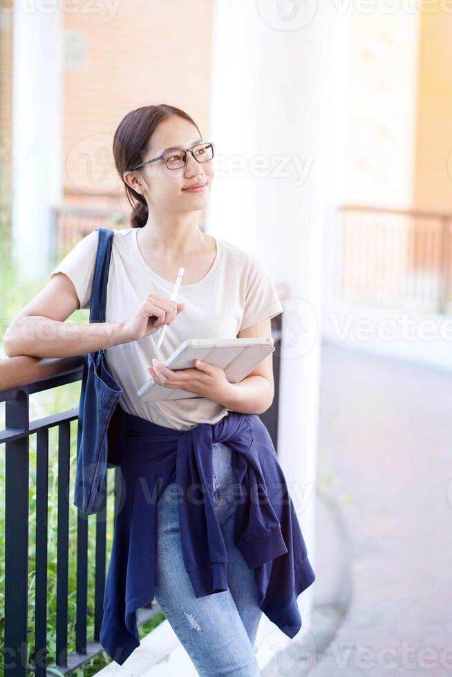 Happiness cheerful Asian young female student in casual cloth standing and relaxing on the school building. Asian school concept. photo